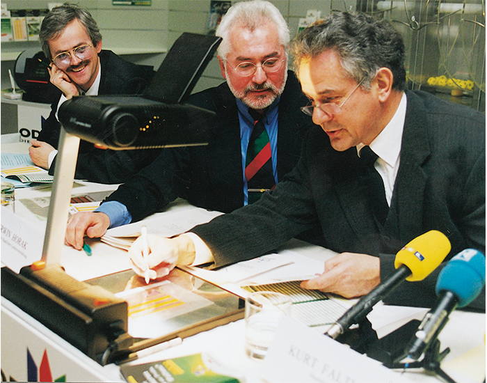 1999: Am 19. Februar wird „ODDSET – Die Sportwette mit festen Gewinnquoten“ in Bayern eingeführt. LOTTO Bayern Präsident Erwin Horak (Mitte) und der bayerische Finanzminister Kurt Faltlhauser (rechts) füllen den ersten Wettschein aus. National federführend für Organisation und Überwachung des ODDSET Spielgeschäfts ist die Staatliche Lotterieverwaltung Bayern. Spielplangestaltung, Quotenfestlegung und Marketing erfolgen zentral von München aus.